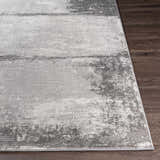 Close-up of the Coombs Area Rug, showcasing its charcoal, gray, and light gray abstract pattern and machine-woven texture. Front
