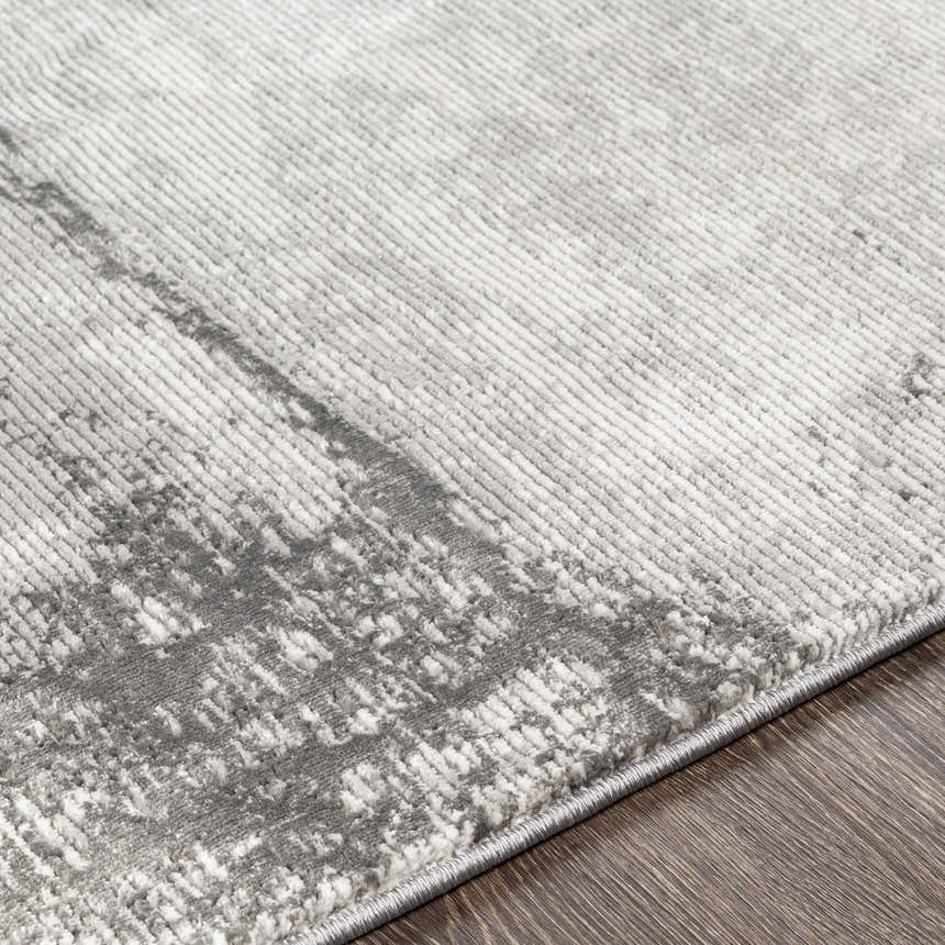 Close-up of the Coombs Area Rug showing its charcoal, gray, and light gray contemporary pattern and machine-woven texture. Texture