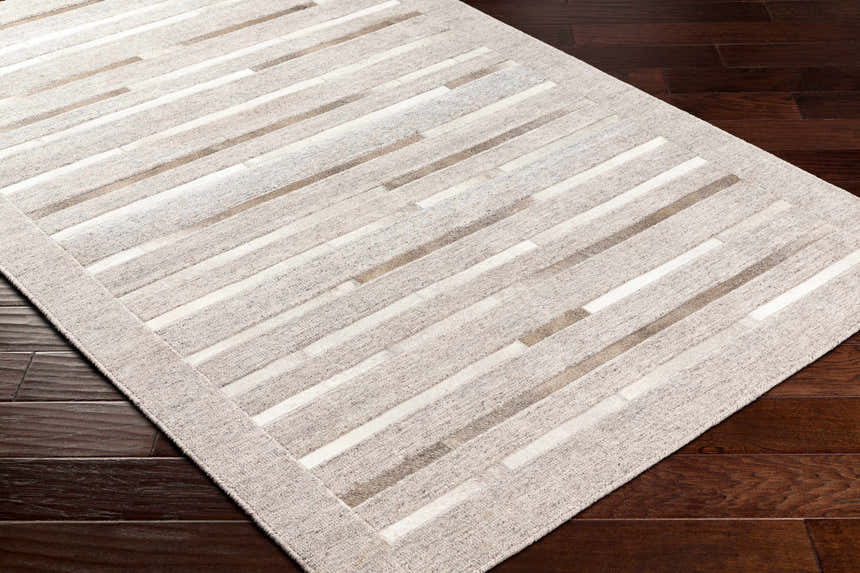 Close-up of Cantu Premium Viscose&Leather Area Rug. Beige, gray, and leather stripes on a dark wood floor. Corner