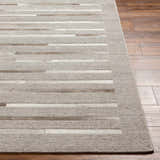 Close-up of Cantu Premium Viscose & Leather Area Rug. Beige, light gray geometric pattern. Hair on hide and leather details. Front