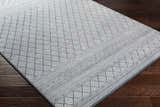 Close-up of Centertown Area Rug. Blue and ivory geometric pattern. Farmhouse style rug on dark wood floor. Corner