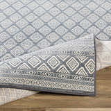 Close up of the Centertown Area Rug, featuring a blue and ivory geometric diamond pattern. Fold