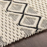 Close-up of the hand woven Cobourg Area Carpet. Black geometric pattern on cream 100% wool rug. Farmhouse style. Texture