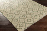 Coffeyville jute rug, cream and sage geometric pattern, fringed edge, on dark wood floor. Handcrafted, contemporary style. Corner