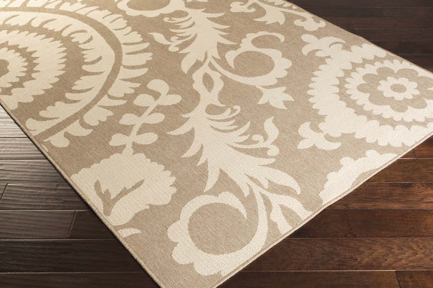 Close-up of the Collegeport Area Rug. Light beige and brown floral pattern on a machine-woven olefin rug. Corner