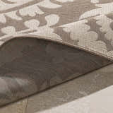 Close-up of the Collegeport Area Rug showing its light beige floral pattern on a light brown background and its backing. Fold