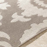 Close-up of the Collegeport Area Rug. Light beige floral pattern on a light brown, machine-woven olefin rug. Texture