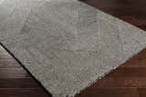 Close-up of the hand-tufted Conshohocken Area Rug. Black and cream wool rug with a contemporary geometric pattern. Corner
