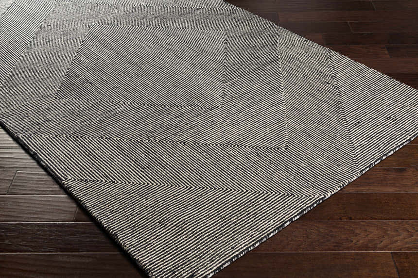 Close-up of the hand-tufted Conshohocken Area Rug. Black and cream wool rug with a contemporary geometric pattern. Corner