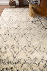Living room scene with a cream shag Cotgrave trellis rug, wood stump side table, and leather butterfly chair. Styleshot