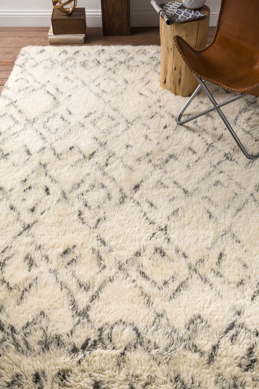 Living room scene with a cream shag Cotgrave trellis rug, wood stump side table, and leather butterfly chair. Styleshot