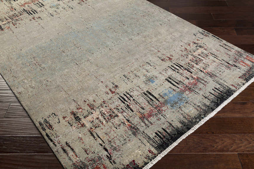 Close-up of the Coudersport Carpet. Hand-knotted wool rug in black, brick red, cream, and sky blue on dark wood floors. Corner