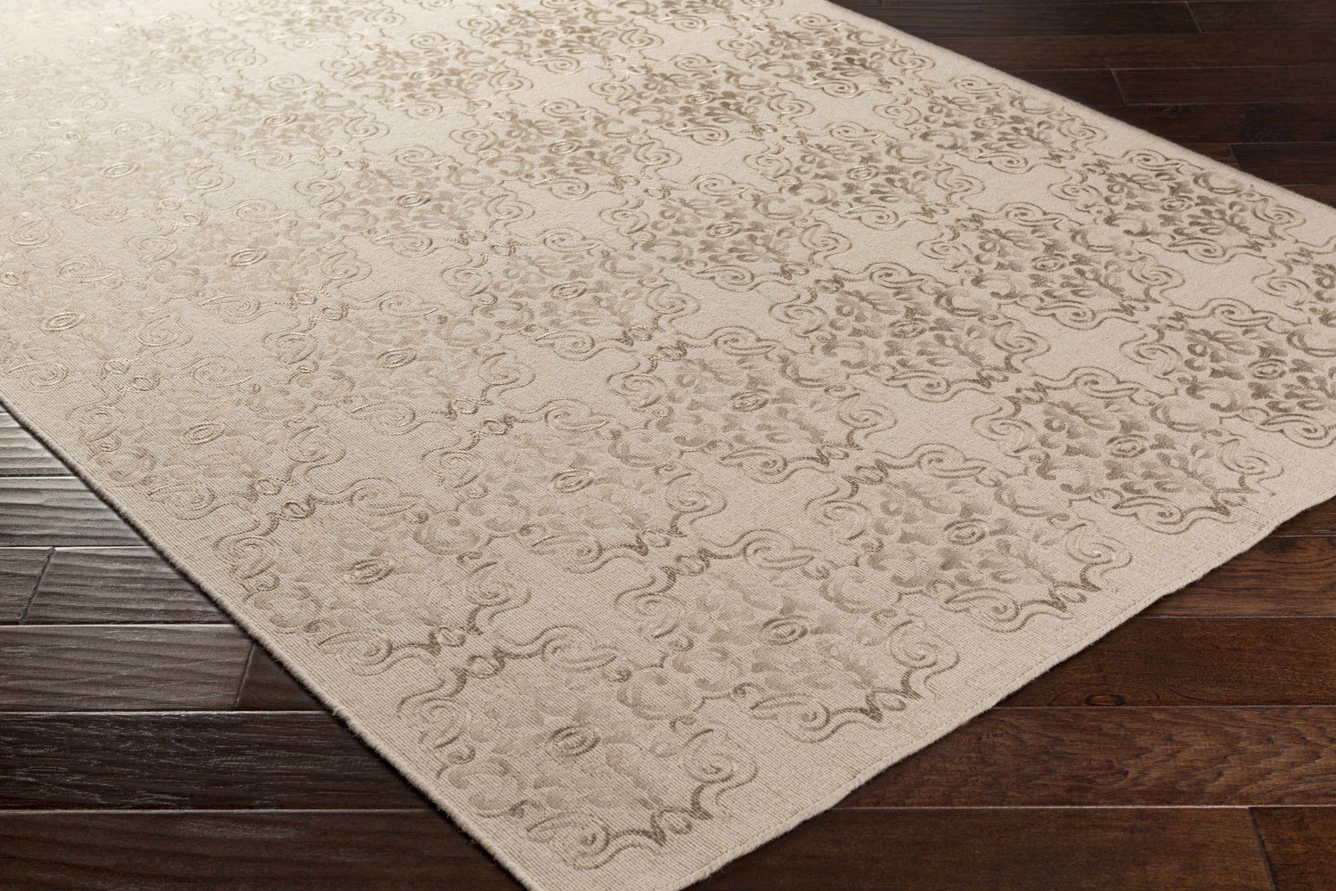 Close-up of the Countyline Area Rug, a hand-woven wool rug with a subtle beige floral pattern on dark wood floors. Corner