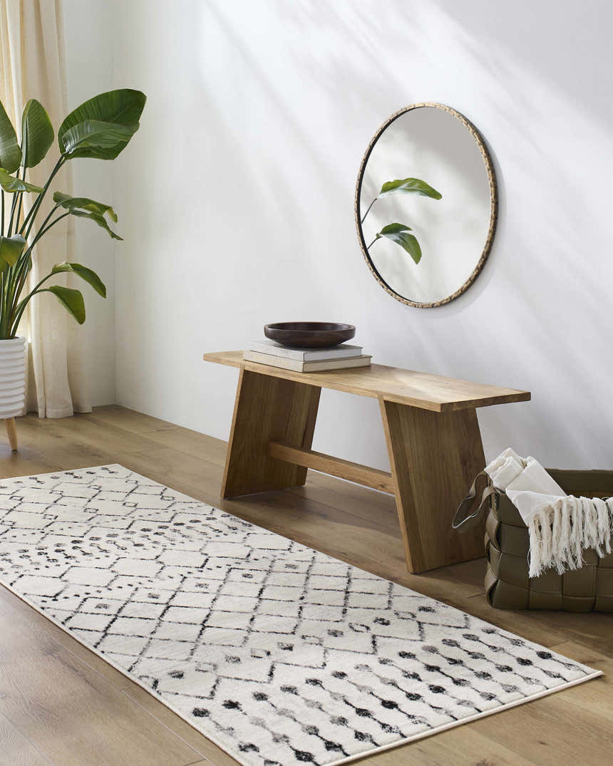 Entryway with a Scandi Moroccan Trellis Rug, wood bench, round mirror, and potted plant for a bright, minimalist look. Roomscene-Runner