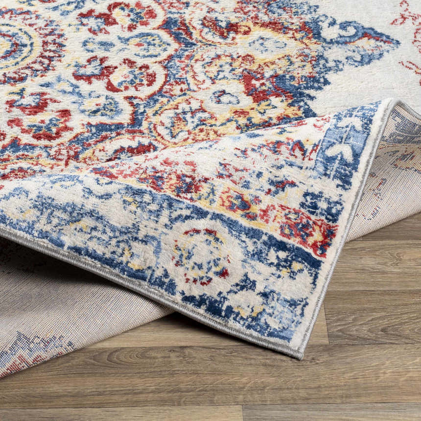Close-up of the Carron Area Rug showing the farmhouse style, blue, red, and yellow traditional pattern and machine woven texture. Fold