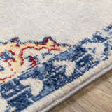 Close-up of the Carron Area Rug showing its traditional blue, red, and yellow pattern and soft, textured polypropylene weave. Texture