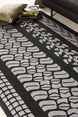 Close-up of the Cressona Area Rug, a black and gray hand-hooked rug with a contemporary tire track pattern. Styleshot