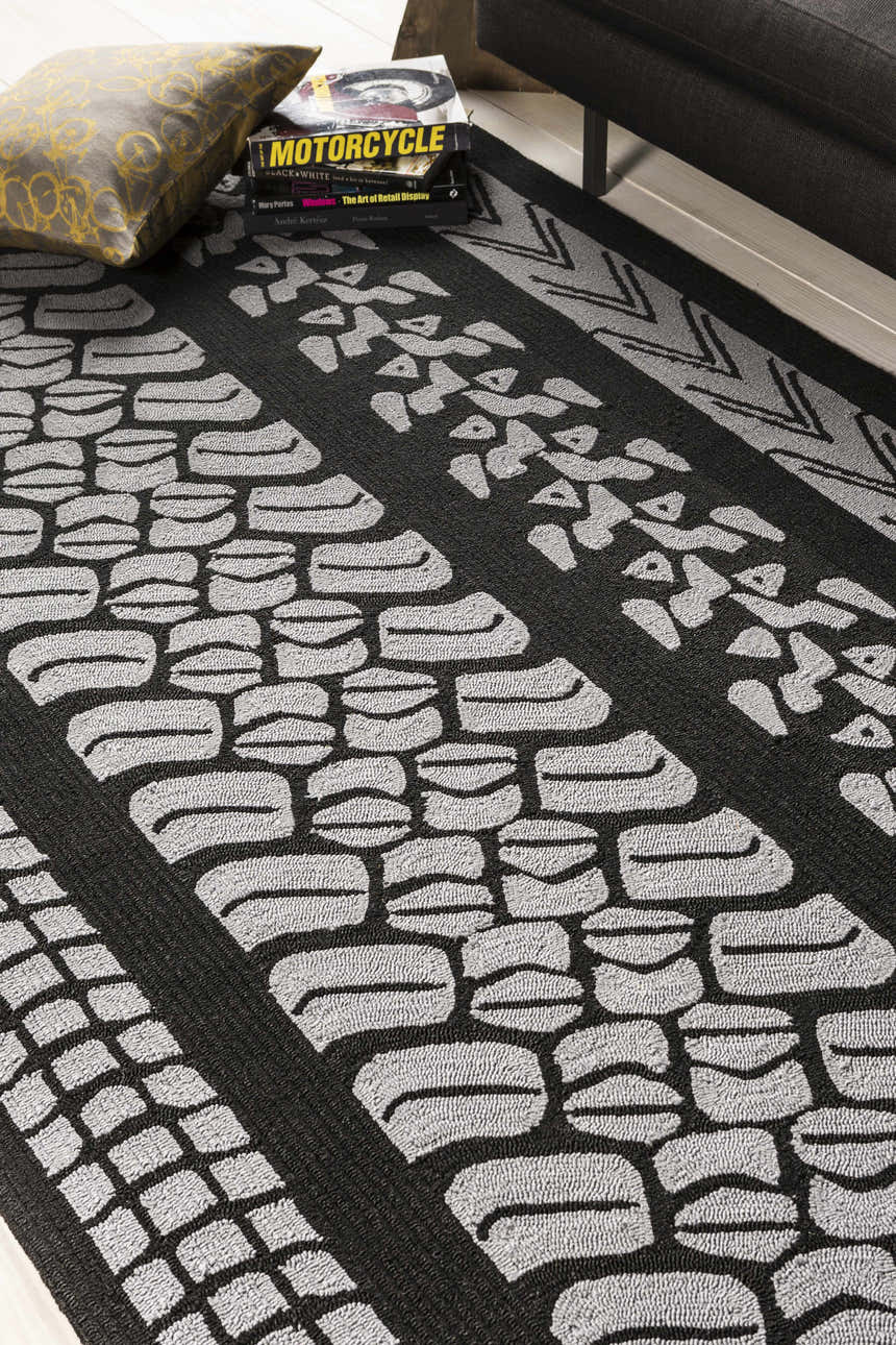 Close-up of the Cressona Area Rug, a black and gray hand-hooked rug with a contemporary tire track pattern. Styleshot