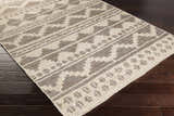 Close-up of the hand woven Cresco Jute Carpet. Farmhouse style rug in charcoal, dark brown, and ivory on dark wood floors. Corner