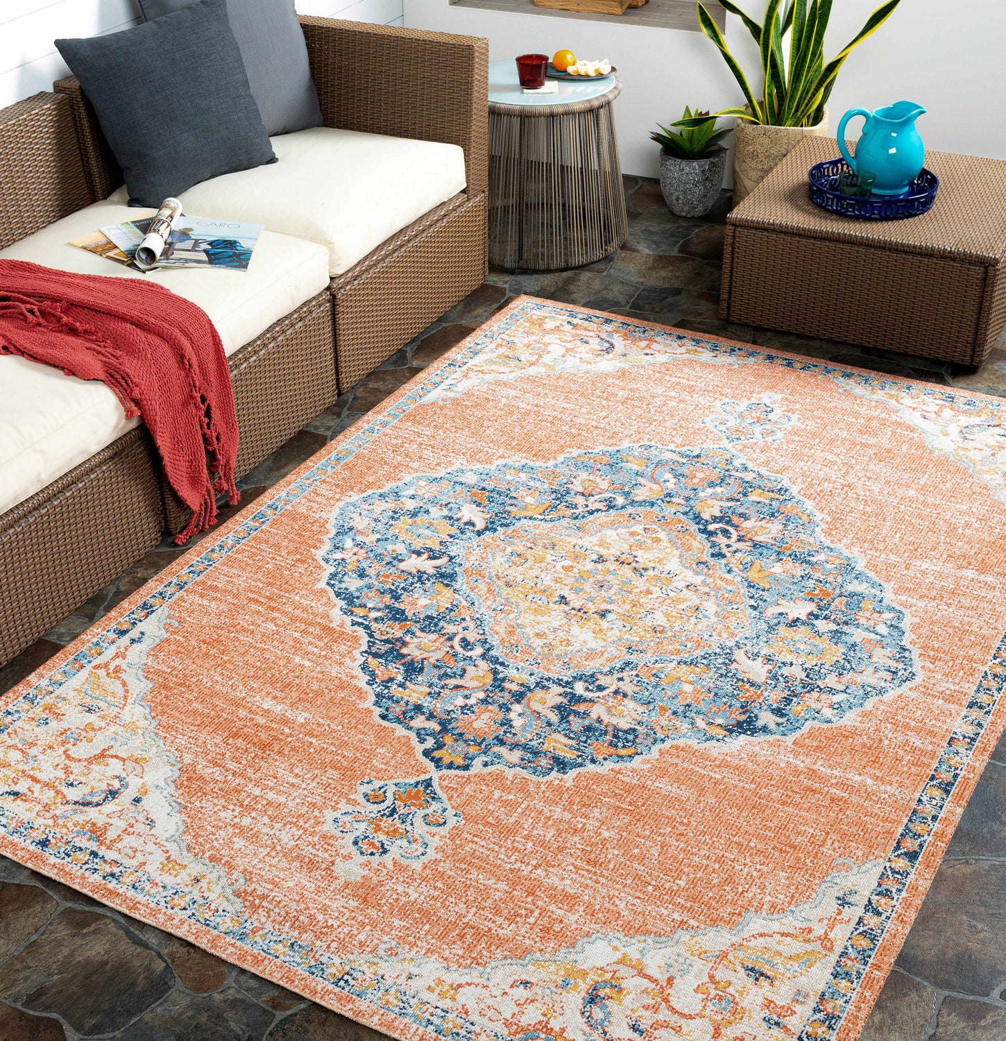 Outdoor patio scene with wicker furniture and Cottesloe Area Rug in orange, blue, and cream oriental design. Roomscene-Rectangle