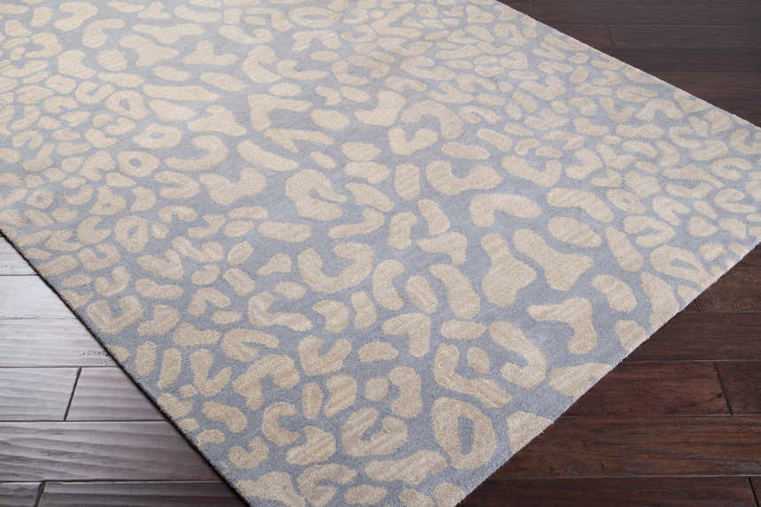 Close-up of the Curwensville Leopard Print Area Rug. Slate blue wool with a taupe animal print pattern. Hand-tufted texture. Corner