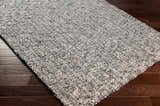 Close-up of the hand-loomed Cushendall Premium Rug. Dark blue and off-white contemporary design on wood floor. Corner