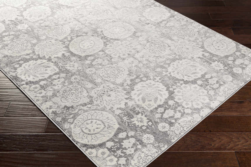 Close-up of the Cwm Area Rug showing its charcoal, light gray, and off-white contemporary floral design. Corner