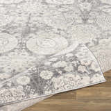 Close-up of the Cwm Area Rug, a clearance item with charcoal, gray, and off-white contemporary floral pattern. Fold