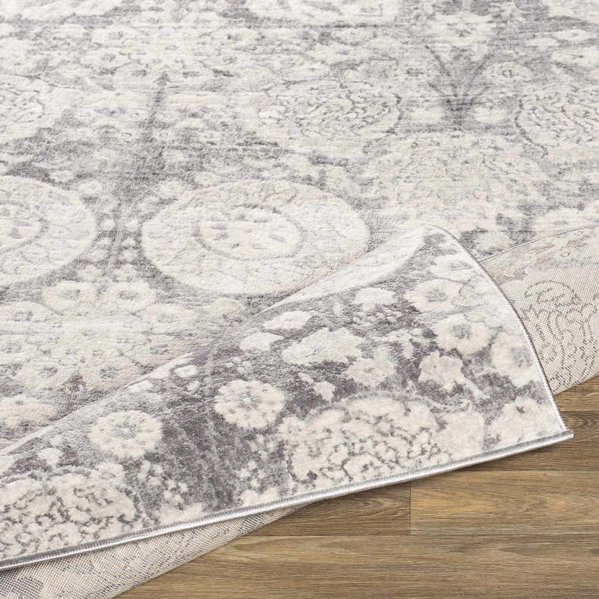 Close-up of the Cwm Area Rug, a clearance item with charcoal, gray, and off-white contemporary floral pattern. Fold