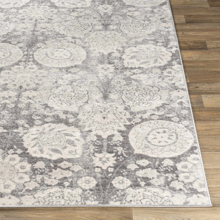 Close-up of the Cwm Area Rug, a charcoal and light gray contemporary rug with a floral medallion pattern on wood floors. Front