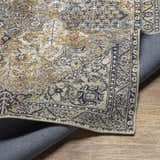 Close-up of the Dagatan Washable Area Rug showing its beige, black, and camel traditional pattern and machine woven construction. Fold