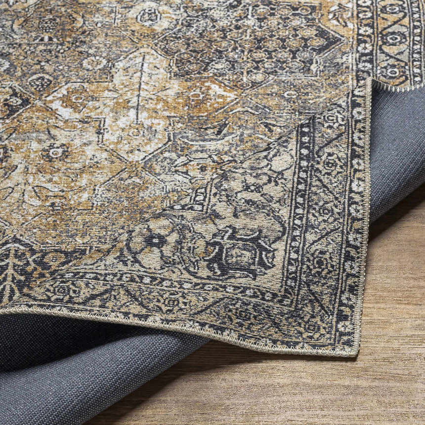 Close-up of the Dagatan Washable Area Rug showing its beige, black, and camel traditional pattern and machine woven construction. Fold