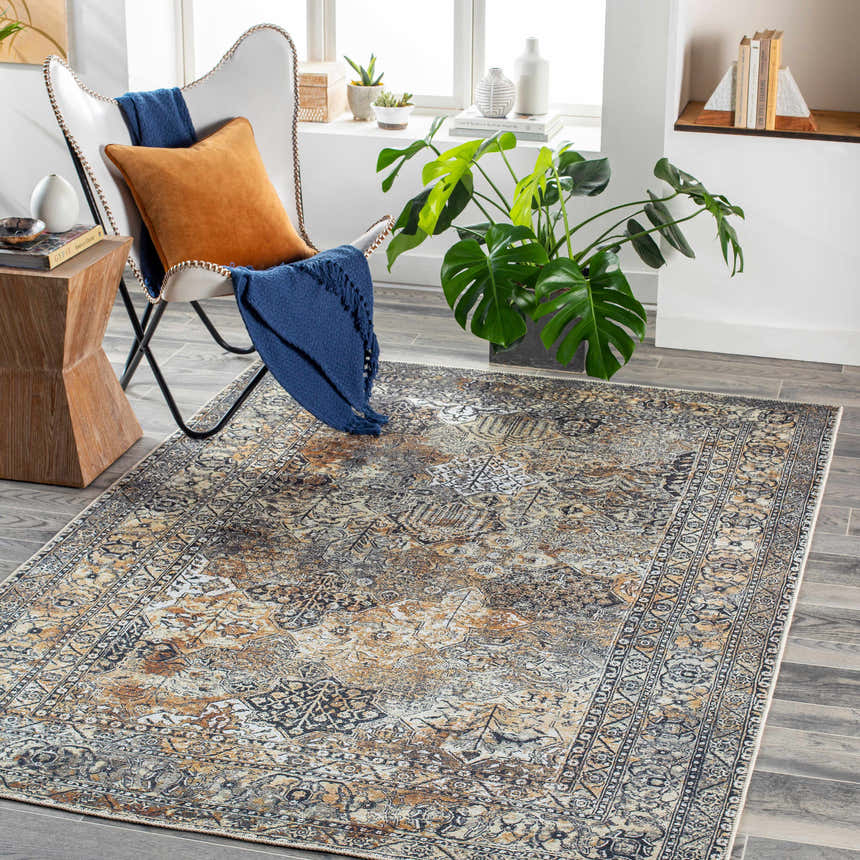Living room scene with a beige, black, and camel Dagatan Washable Area Rug, white chair, and wood accents. Roomscene-Rectangle