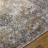 Close up of the Dagatan Washable Area Rug. Beige, black, and camel oriental rug pattern on a wood floor. Texture