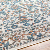 Close up of the Dagny Area Rug showing its traditional floral pattern in cloud gray, light gray, and nutmeg. Texture