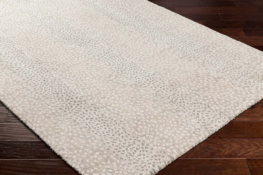 Close-up of the beige and gray Daiva Luxe Rug showing its subtle dotted pattern and soft texture on dark wood flooring. Corner