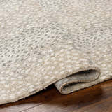 Close up of the beige Daiva Luxe Rug showing its textured, contemporary design and machine-woven construction. Fold