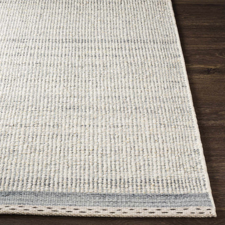 Close up of the Dalaoig rug, a flat woven wool rug in cream and charcoal on a dark wood floor. Front