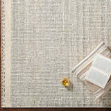 Close-up of the Dalaoig Flat Woven Wool Rug in cream and gray. Hand-woven texture with a book and drink for a cozy feel. Styleshot