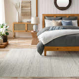 Bedroom scene with a cream Dalaoig Flat Woven Wool Rug, wood bed, and neutral decor creating a calm, transitional style. Roomscene-Rectangle