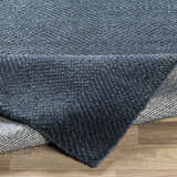 Close-up of the hand-knotted Dateland Area Rug showing its navy and pale blue wool and viscose texture and herringbone pattern. Fold