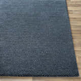 Close-up of the navy Dateland Area Rug showing its hand-knotted wool and viscose texture and herringbone pattern. Front