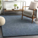 Living room scene with a navy Dateland Area Rug, gray chair, and knit pouf. Roomscene-Rectangle
