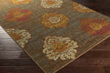 Close-up of the Declo Area Rug showing its floral pattern in burgundy, burnt orange, and brown on a dark brown floor. Corner