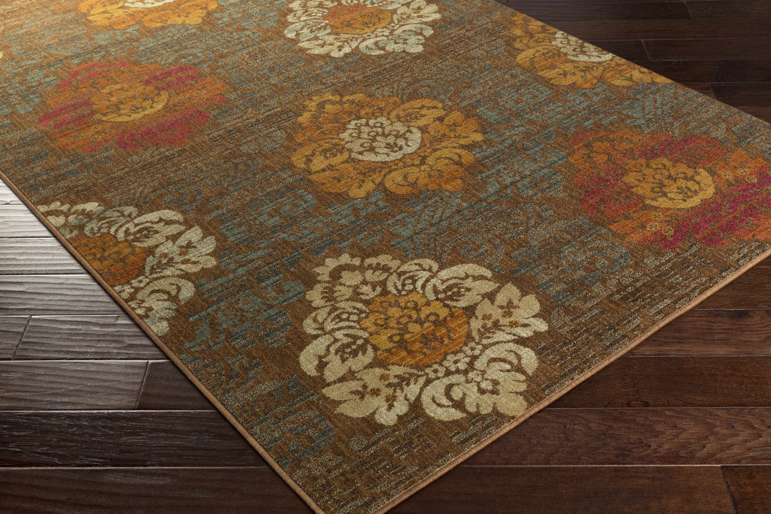 Close-up of the Declo Area Rug showing its floral pattern in burgundy, burnt orange, and brown on a dark brown floor. Corner