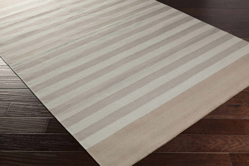 Decordova Area Carpet on dark wood floor. Hand woven cotton rug with charcoal, gray, and medium gray stripes. Corner