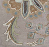 Close-up of the hand-tufted Denio Area Rug. Wool rug with brown, sage, taupe, and sky blue floral pattern on a light brown background. Swatch