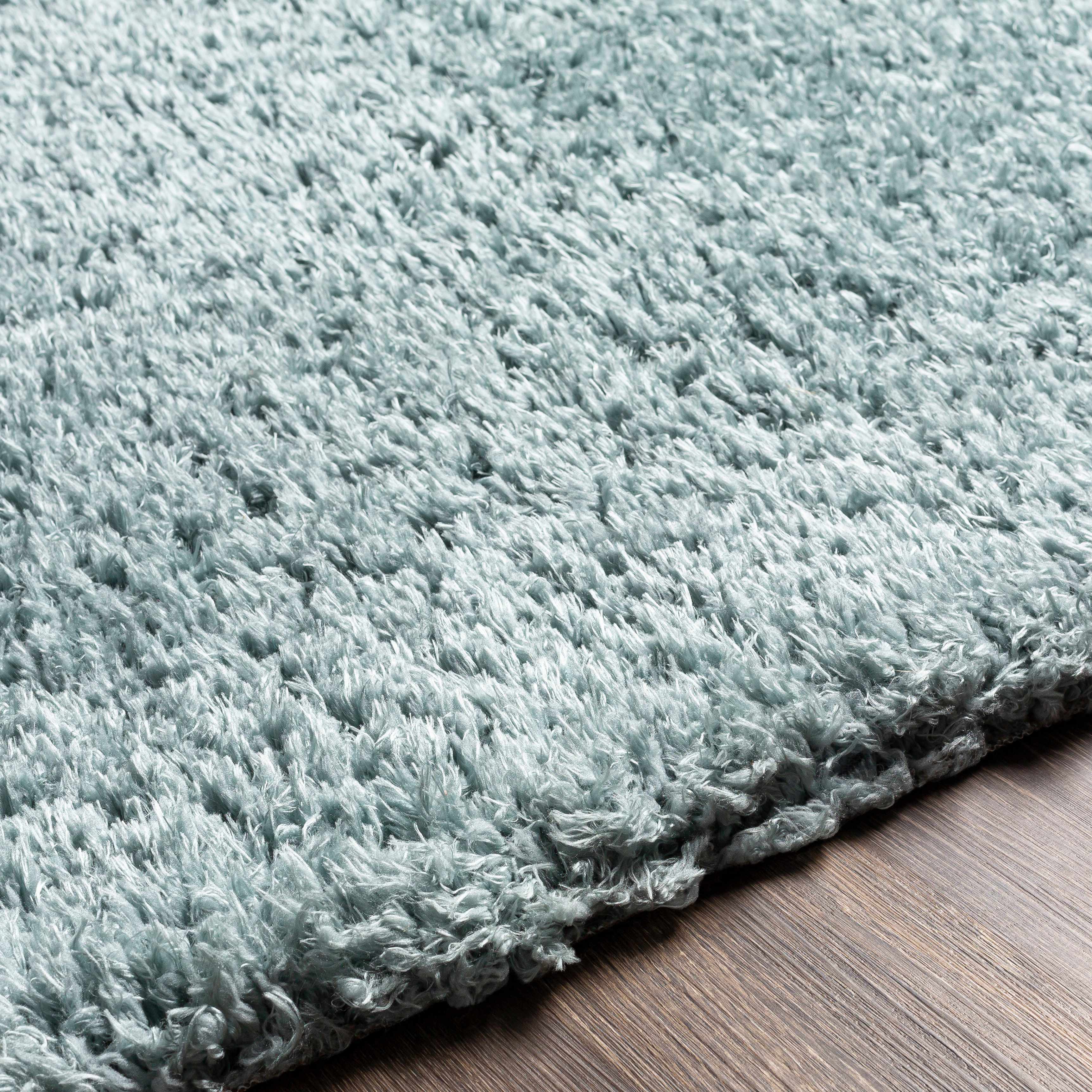 Close-up of the texture on Siari Ice Blue Shag Rug - Clearance, showing fabric weave and feel. Contemporary Area Rug Backing  