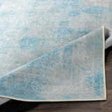 Close up of the Dighton Washable Area Rug, aqua, blue, and light gray traditional pattern. Fold