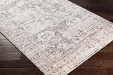 Close-up of the Divisoria Area Rug. Charcoal, cream, gray, light slate, and peach tones with a traditional design. Corner